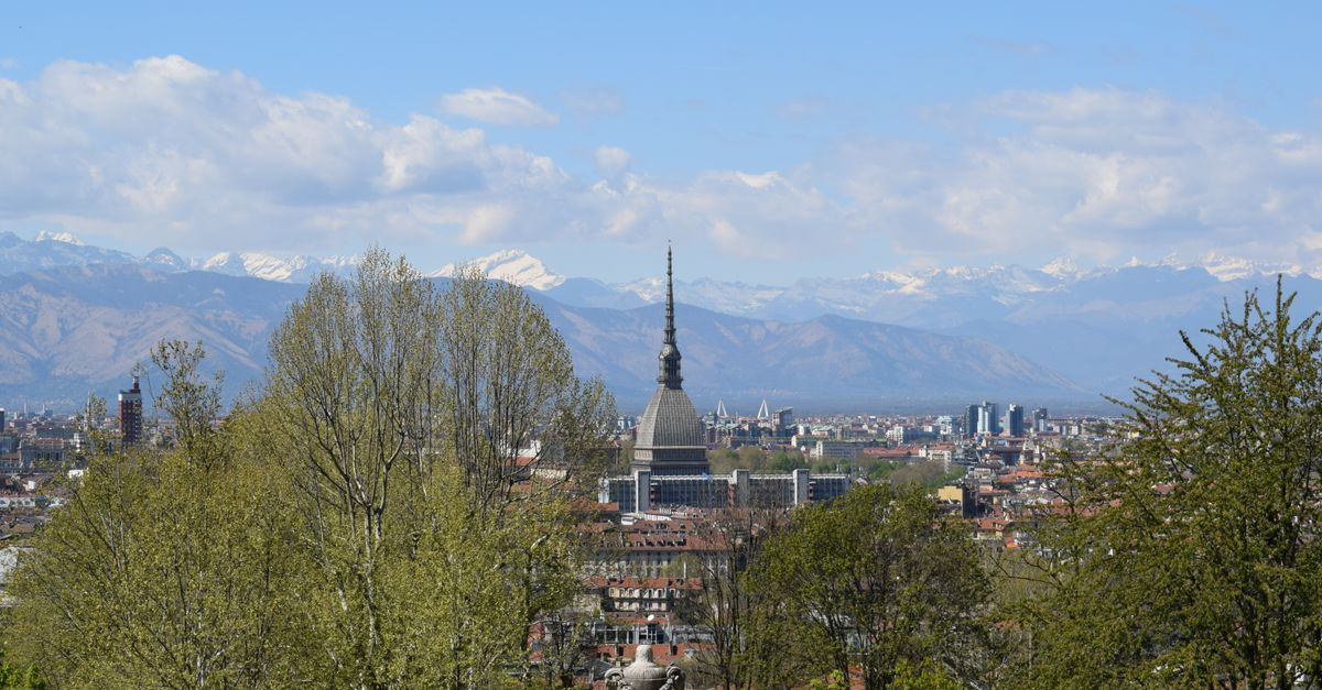 Panoramic view of Turin, Italy, showcasing La Mole Antonelliana and the Alps under a clear blue sky.