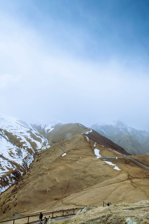 Free Stunning landscape of the Mtskheta-Mtianeti region showcasing snow-dusted mountains and rolling hills under a bright sky. Stock Photo