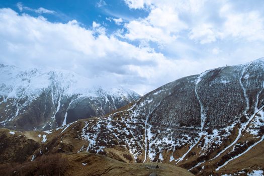 Breathtaking view of snow-speckled mountains under a blue sky in Mtskheta-Mtianeti, Georgia.
