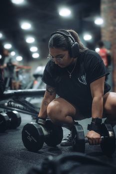 A determined woman working out with dumbbells in a gym setting, showcasing focused fitness training.