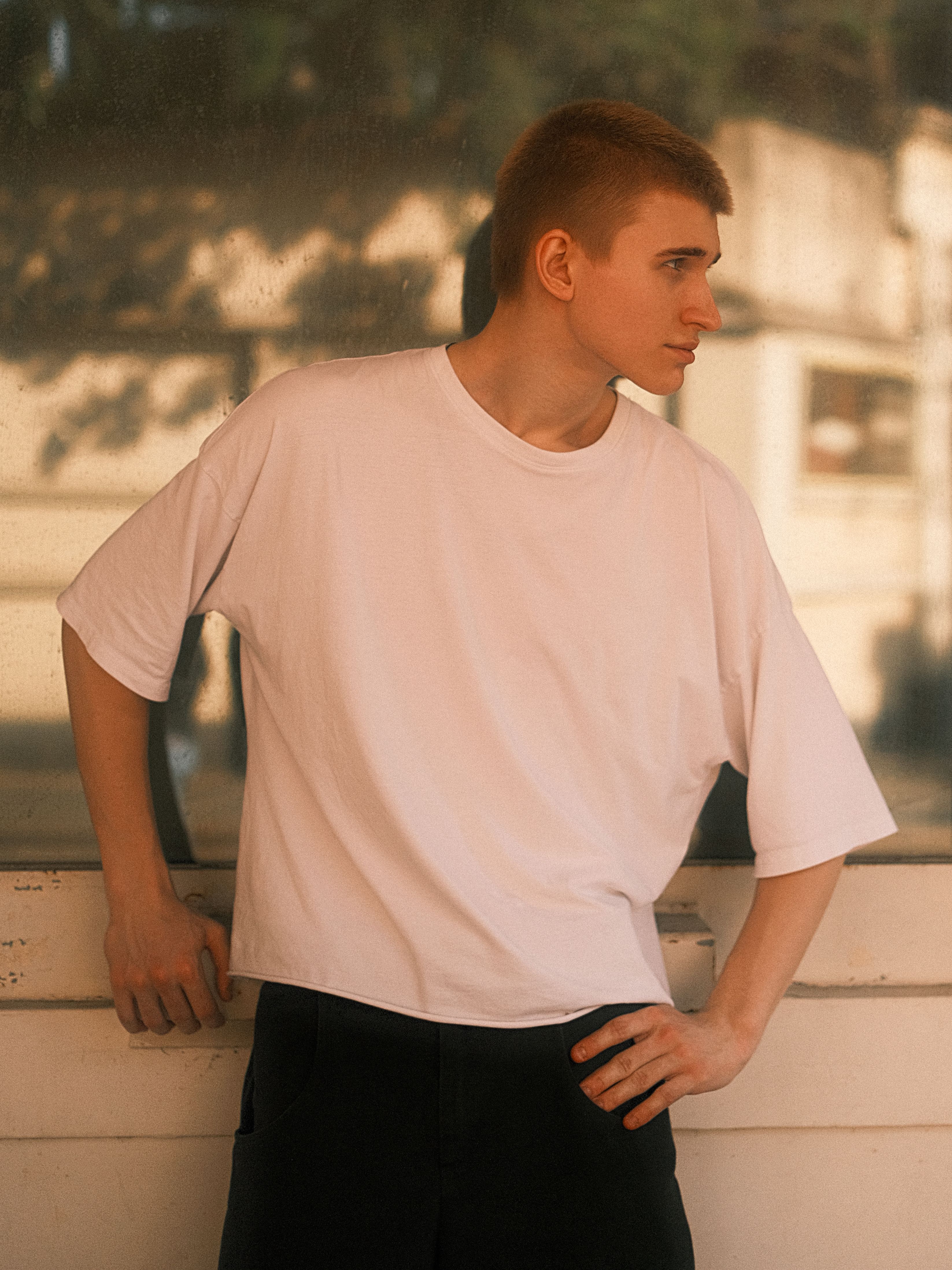 Casual portrait of a young man in a white t-shirt posing outdoors.