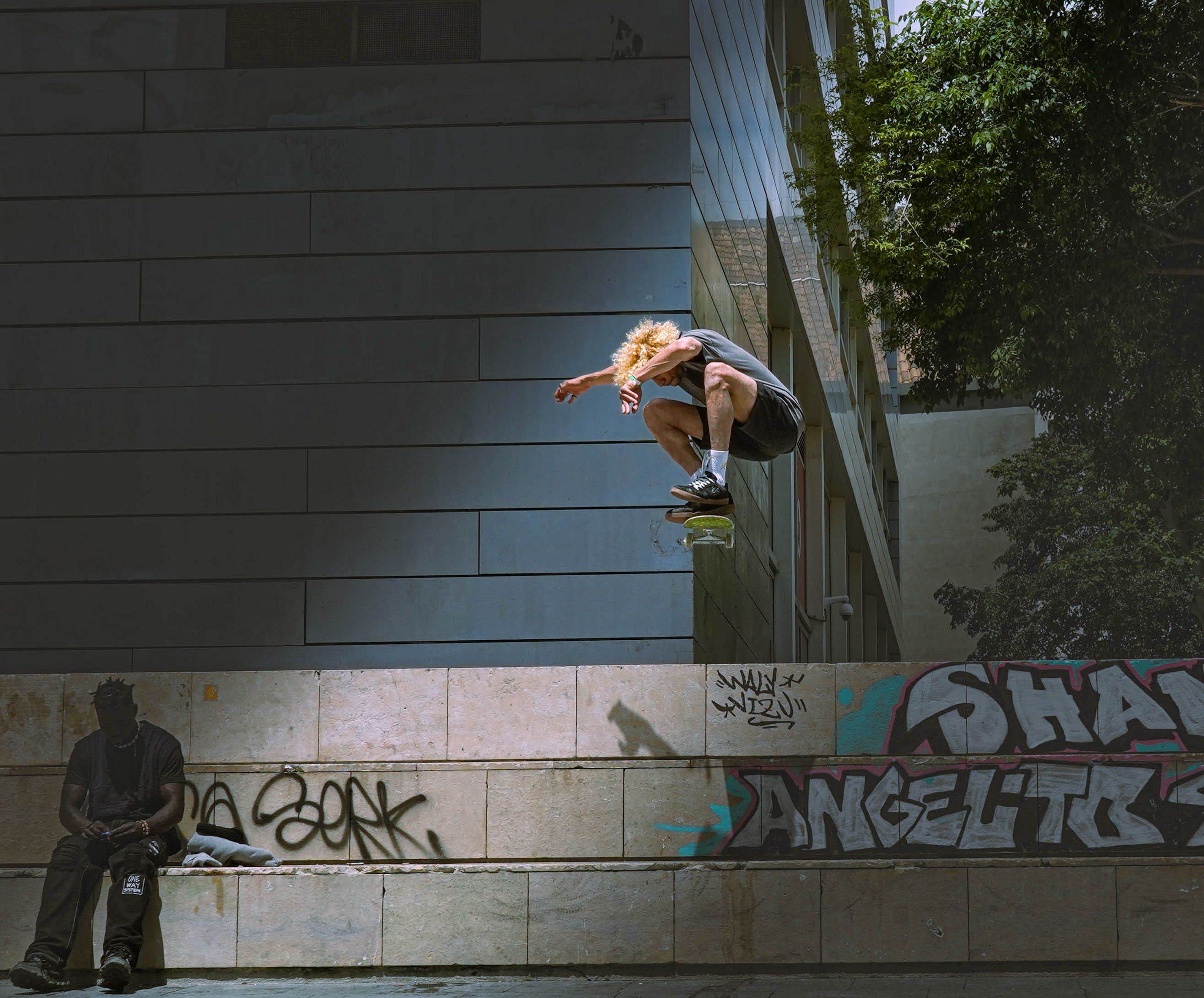 Skateboarder mid-air in Barcelona urban setting with street art and architecture.. skateboarder, barcelona, urban