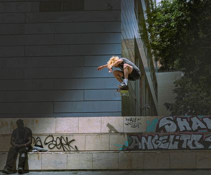 Skateboarder mid-air in Barcelona urban setting with street art and architecture.. skateboarder, barcelona, urban