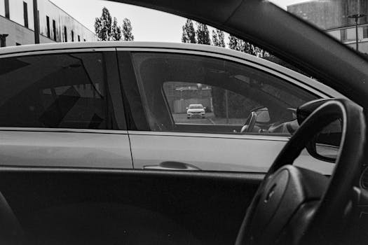 Artistic perspective of a car interior in black and white with street view.