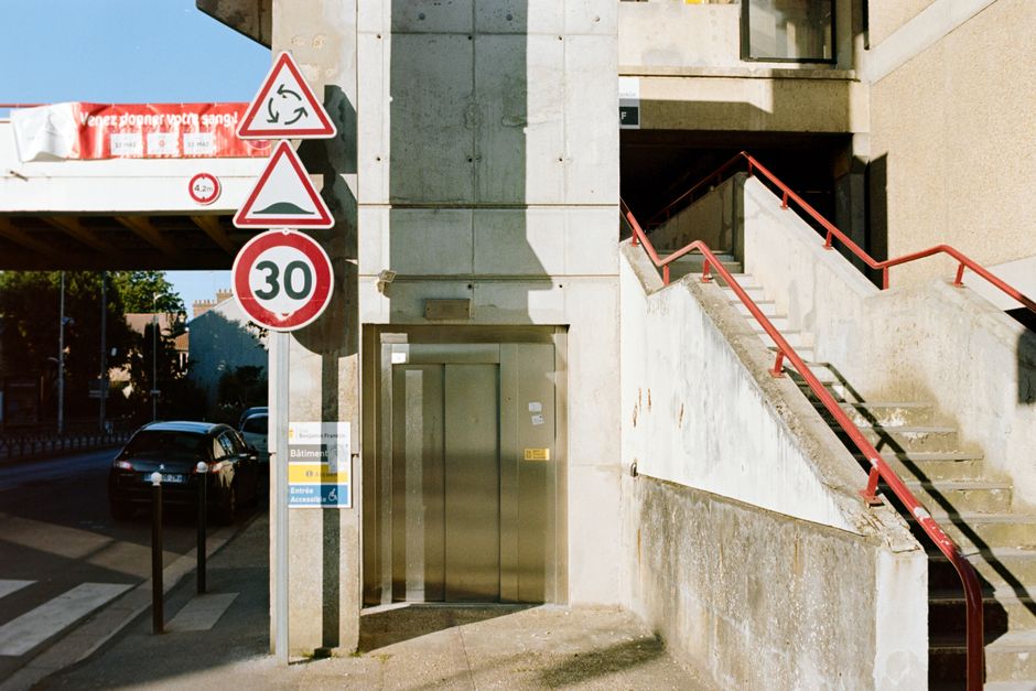 Urban landscape featuring a 30 speed limit sign, concrete structures, and parked cars.