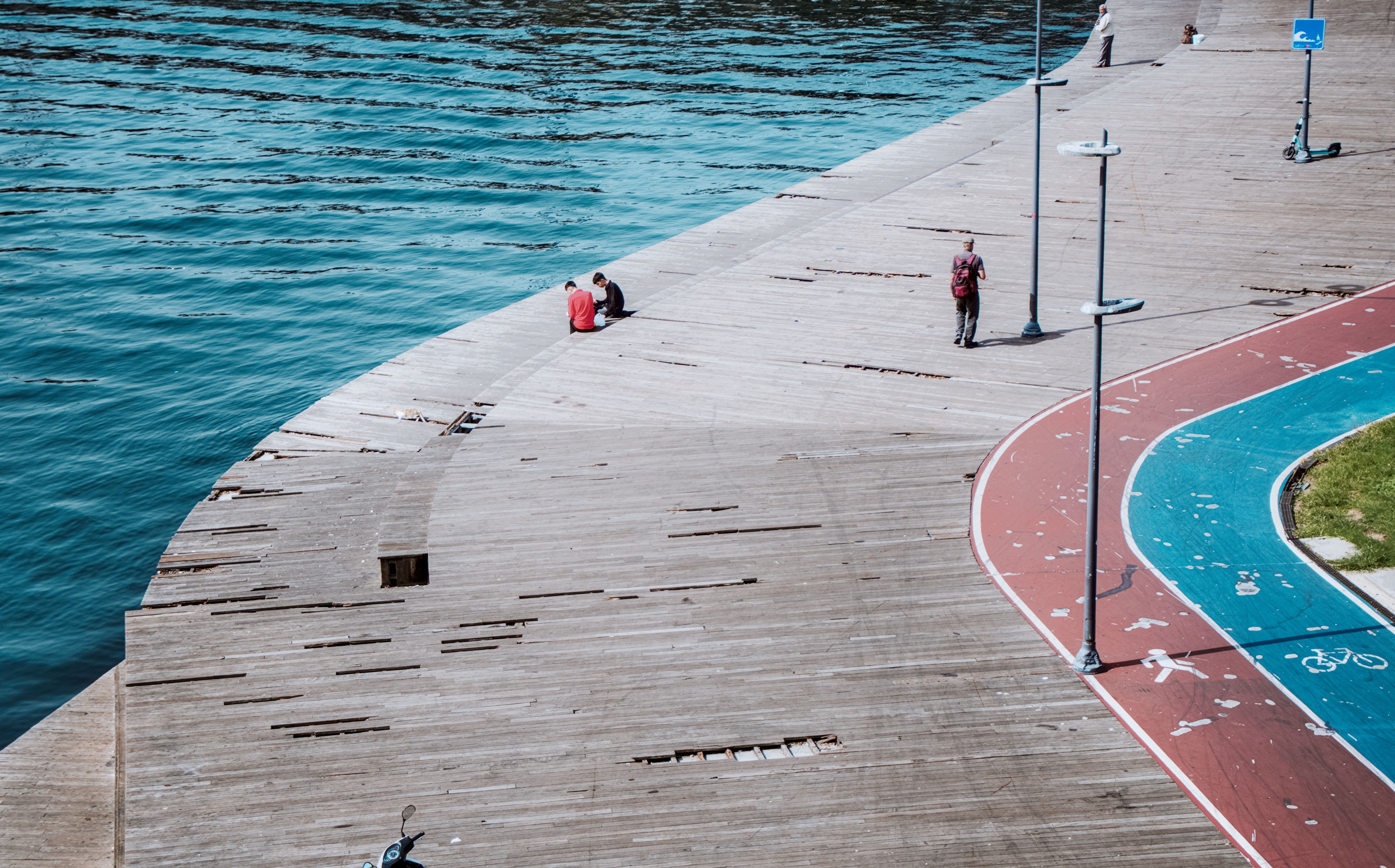 Aerial shot of people relaxing on a waterfront deck in İstanbul, featuring vibrant blue water and a curved pathway.