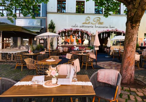 Beautiful outdoor seating at a European cafe with cozy decor and lush greenery.