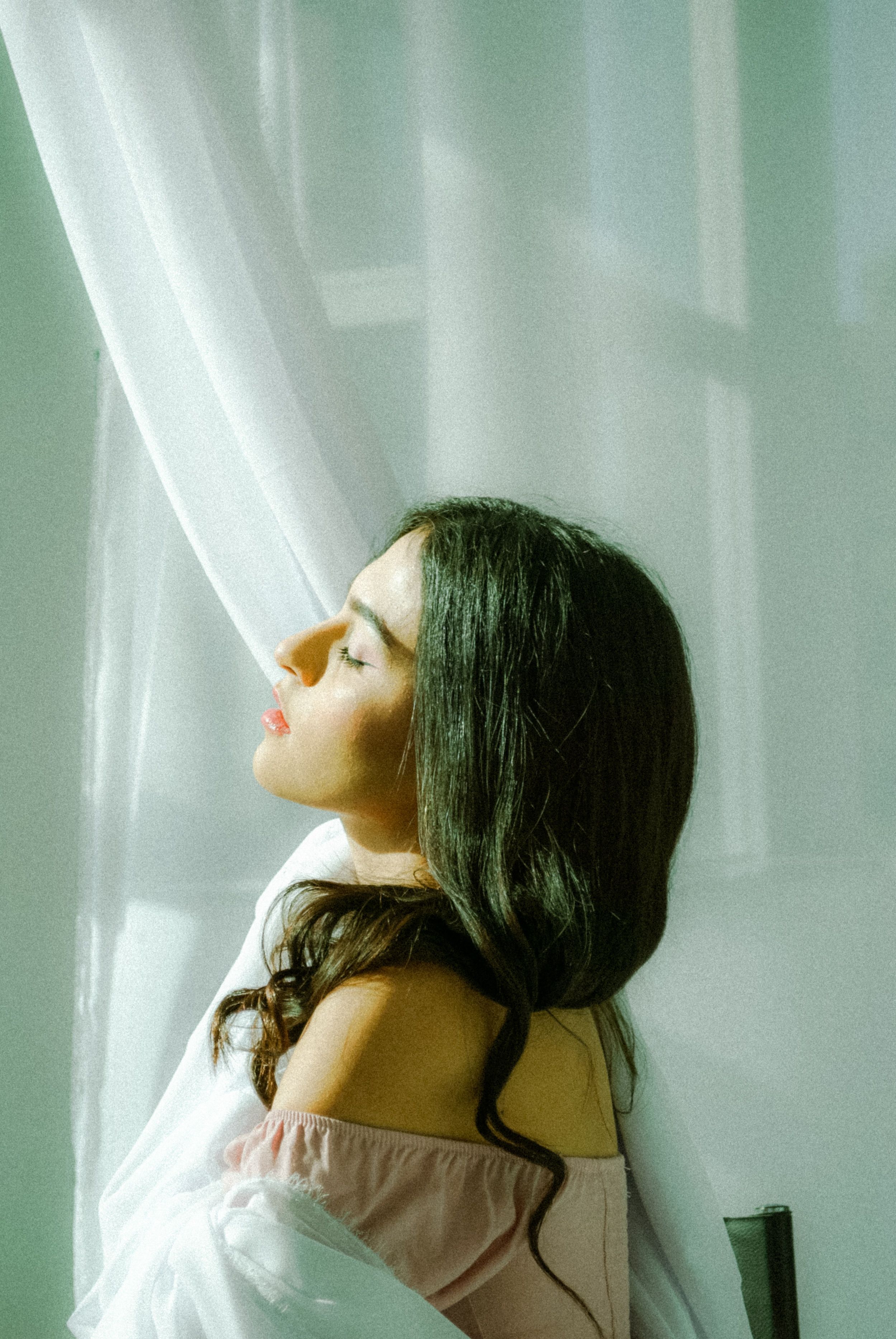 Peaceful moment of a woman in sunlight by a window, enjoying tranquility.