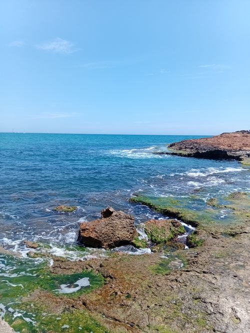 Free Vibrant coastal scene with rocks and blue ocean under a clear sky. Perfect for travel and nature themes. Stock Photo