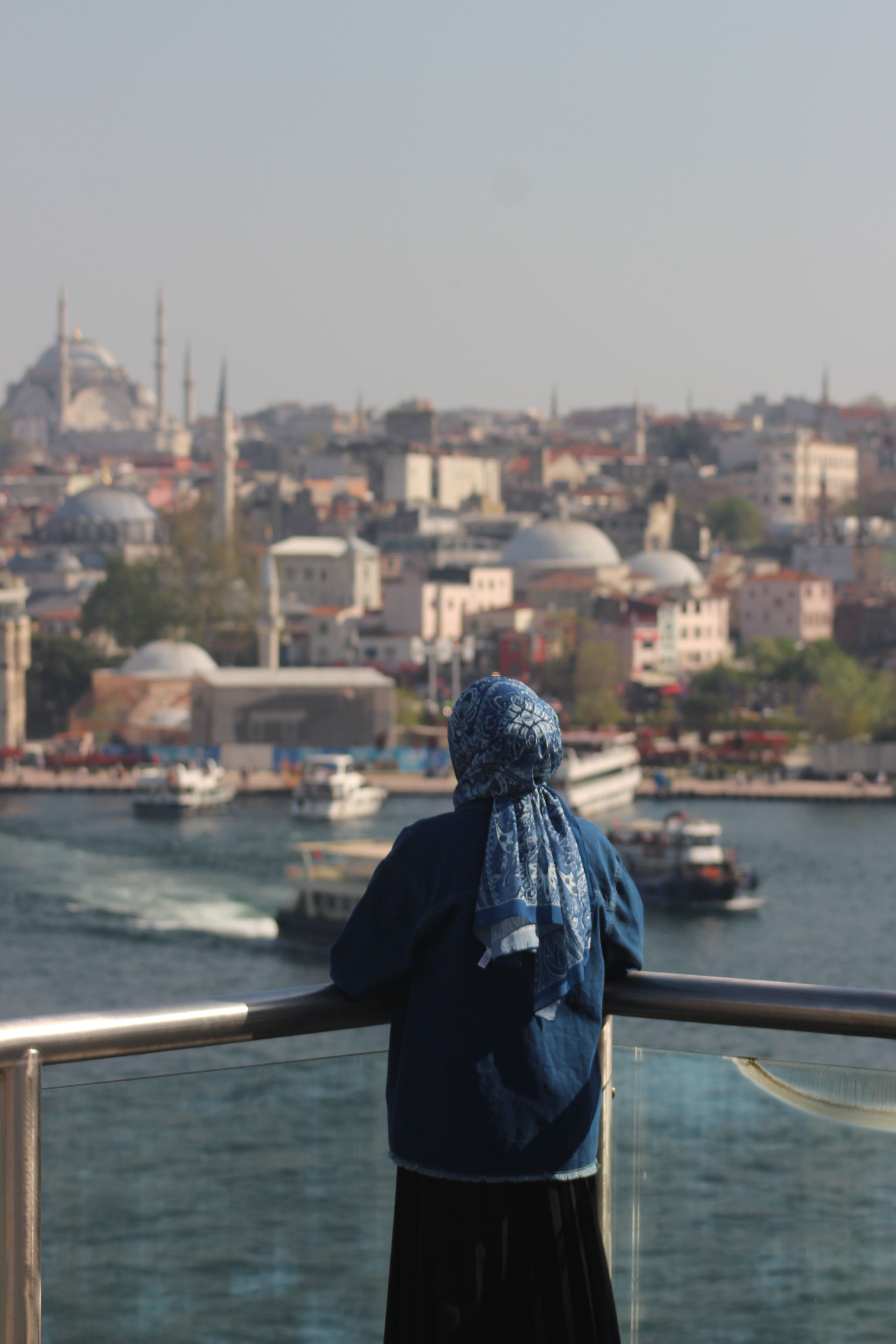 A woman gazes over the Bosphorus in Istanbul, capturing a beautiful cityscape view.