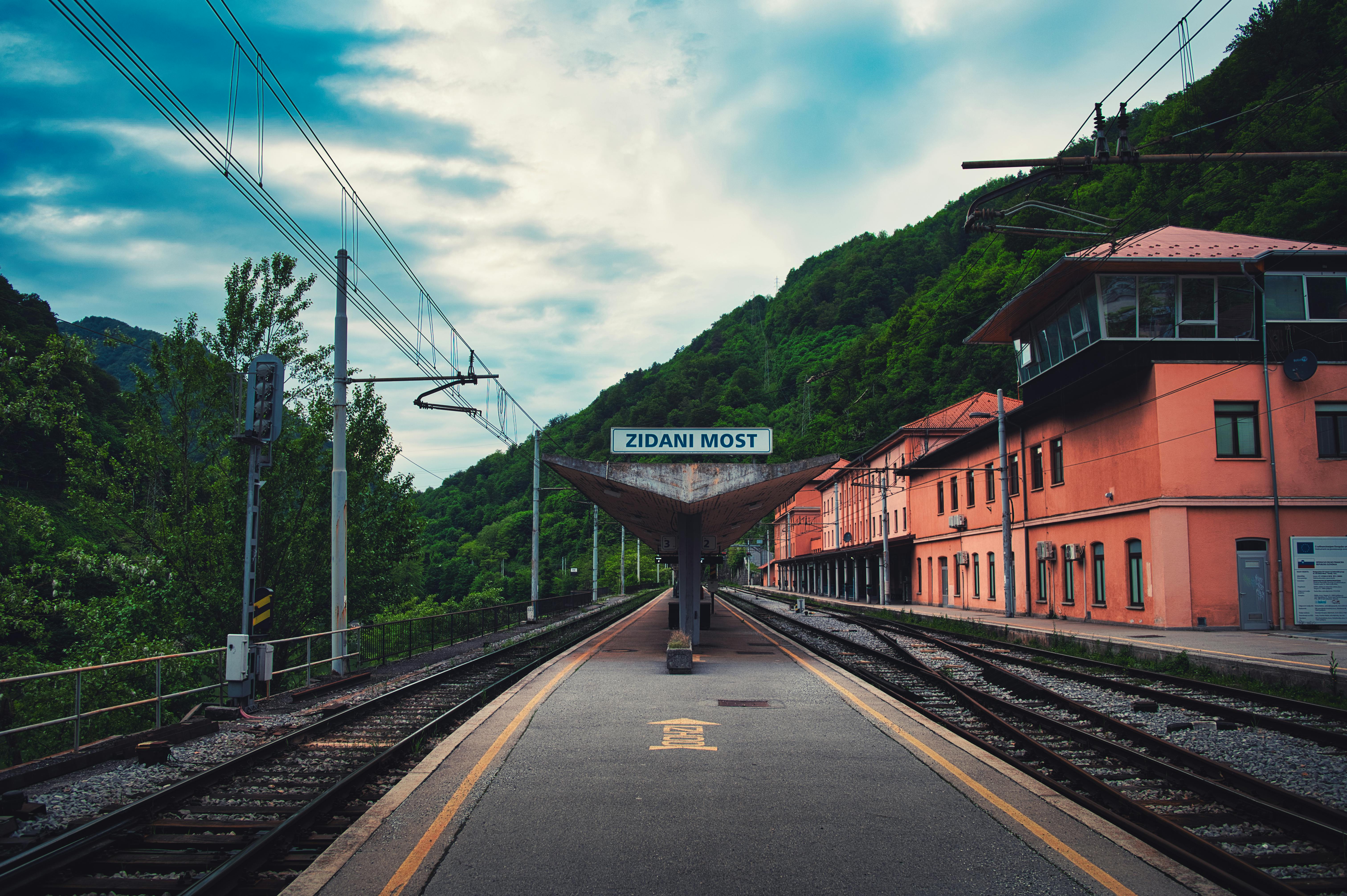 Scenic view of Zidani Most train station nestled in vibrant greenery under a cloudy sky.