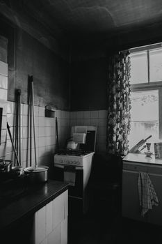 A vintage kitchen interior in black and white with a window and old appliances.
