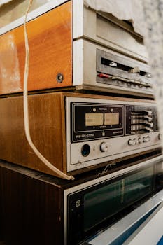 Close-up shot of stacked vintage cassette players and radios with retro style and warm tones.