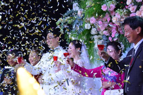 Free A group celebrating a joyous wedding moment with confetti and cheers, surrounded by flowers. Stock Photo