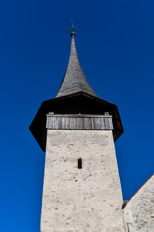 Free A historic church tower in Spiez, Switzerland, beneath a vivid blue sky, showcasing Gothic architecture. Stock Photo