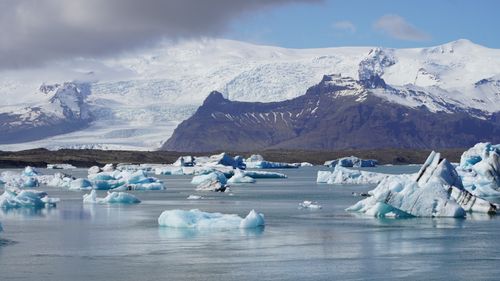 Free Capture the serene beauty of Iceland's glacial lagoon with floating icebergs and majestic mountains. Stock Photo