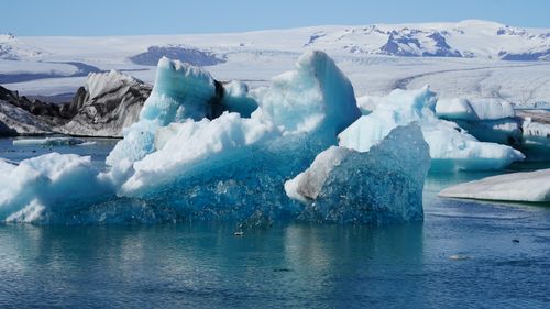 Free Majestic icebergs floating in an Icelandic glacial lagoon against a backdrop of snow-covered mountains. Stock Photo