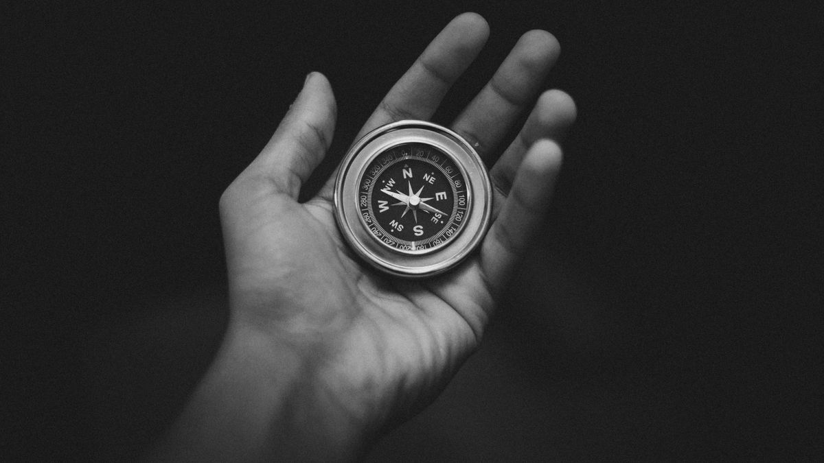 Black and white photo of a hand holding a compass, symbolizing the subconscious mind's hidden influence on direction