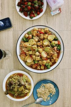 Top view of an Asian-inspired meal with vegetables, tofu, and strawberries, perfect for a colorful dining experience.
