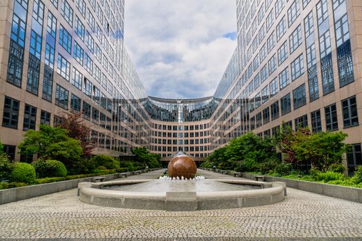 Modern office building with a central fountain and greenery in Berlin, Germany.