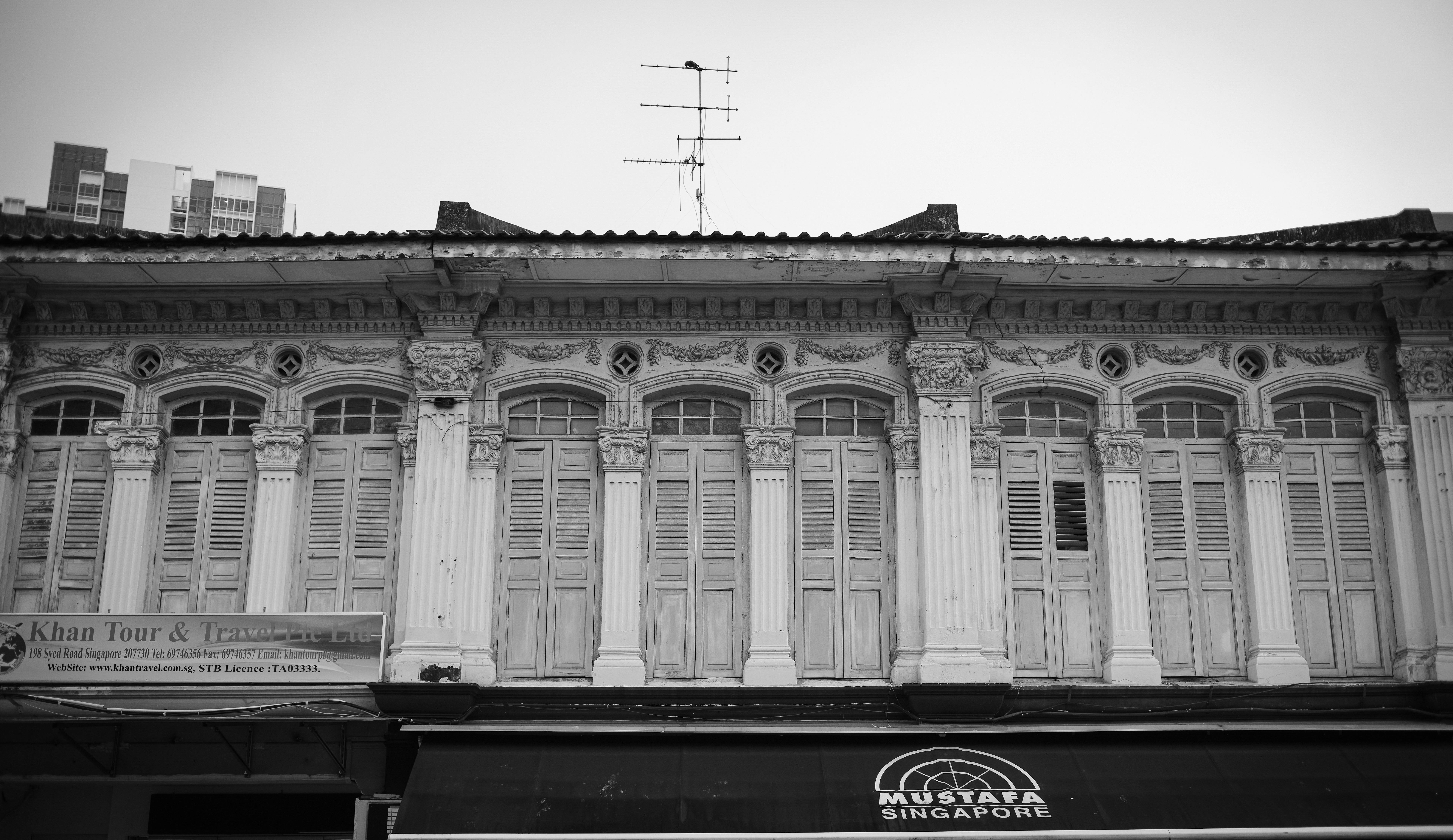 Black and white photo of historical shophouse facade in Singapore, showcasing ornate architectural details.
