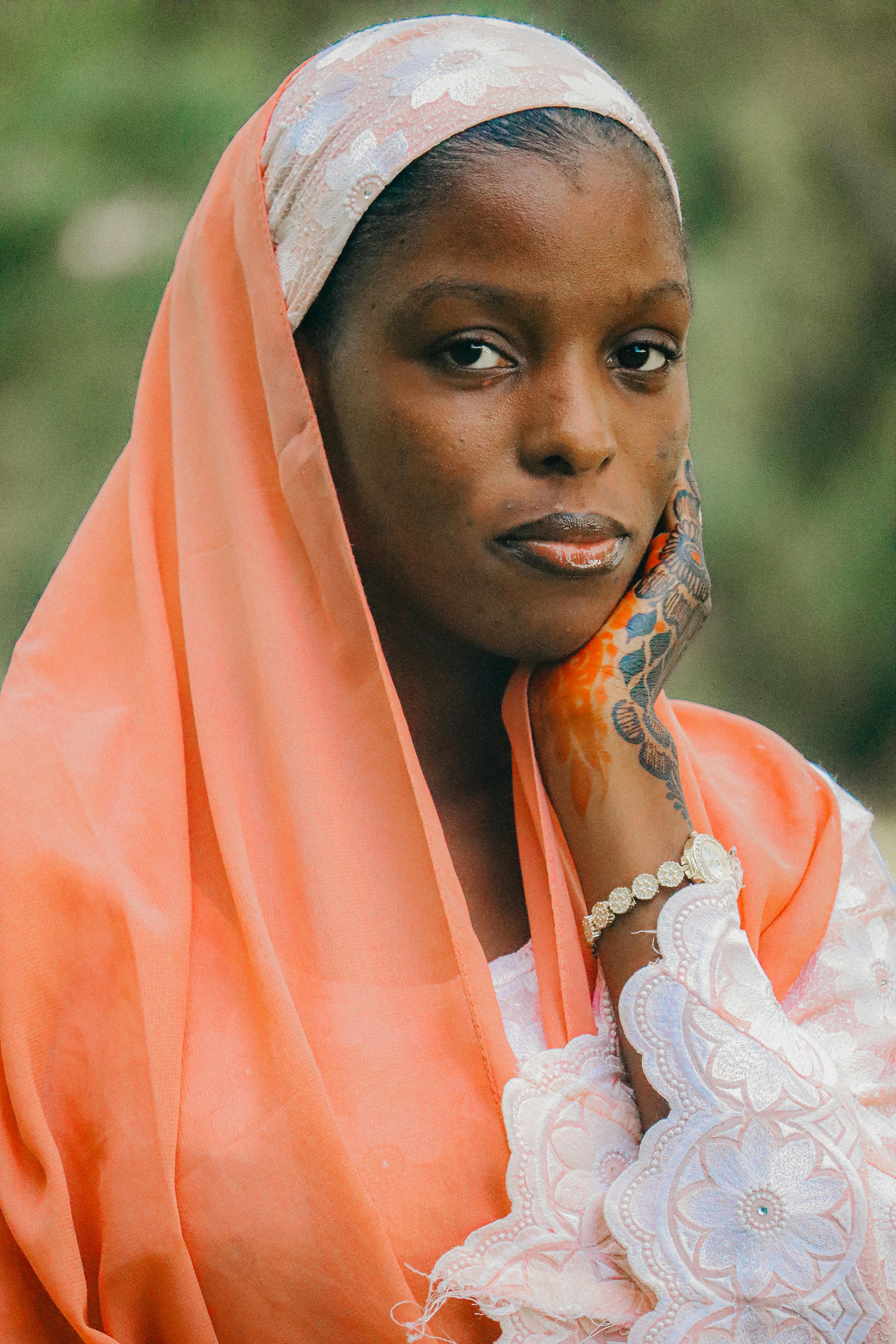 A woman in traditional attire poses outdoors with a serene expression.