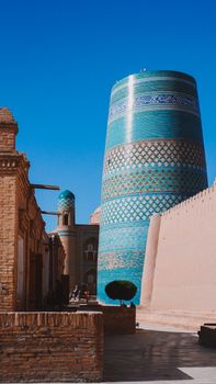 A striking view of the Kalyan Minaret in Khiva, Uzbekistan, showcasing intricate patterns against a clear blue sky.