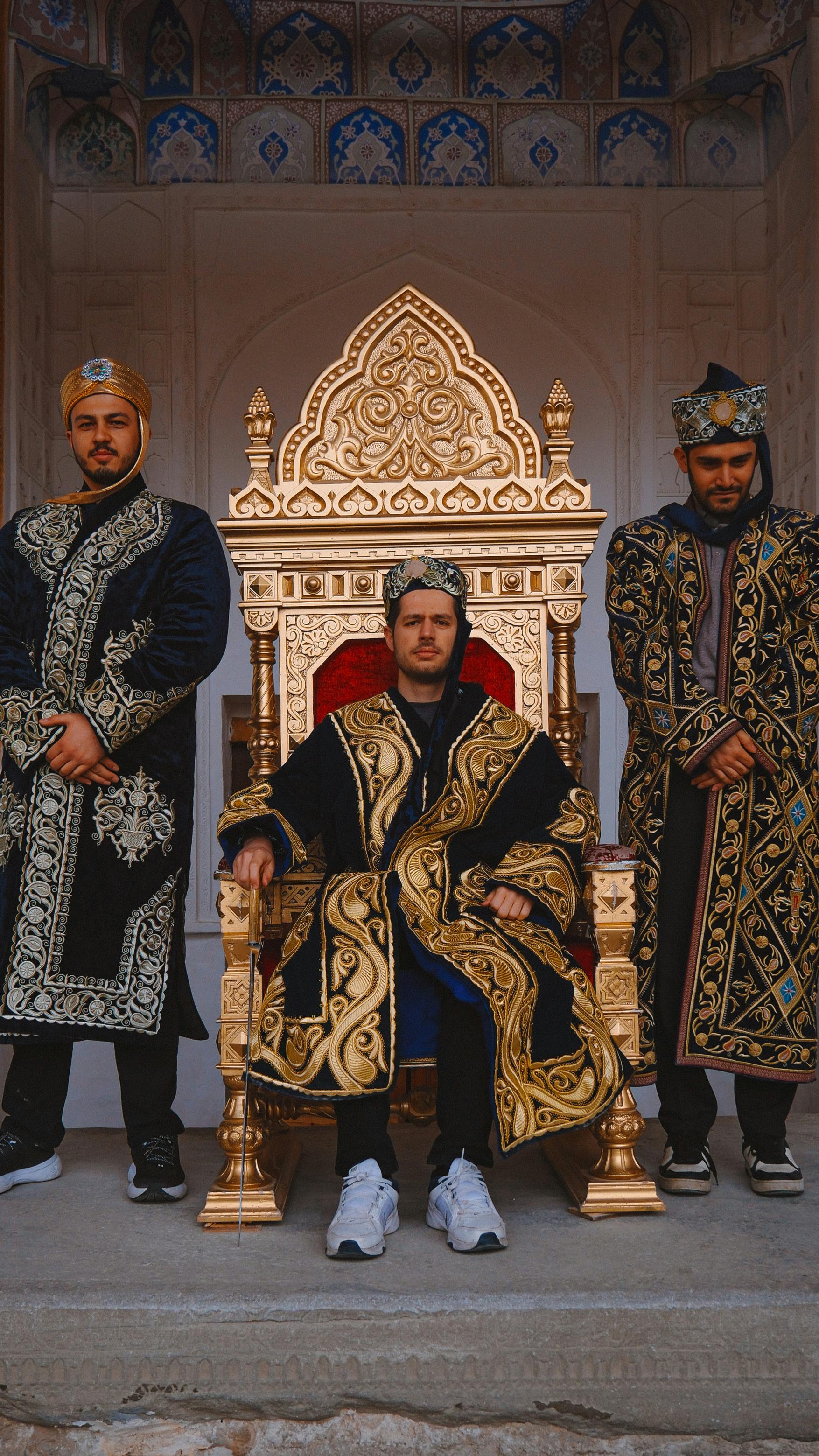 Men in traditional Uzbek clothing seated on a golden throne in Bukhara, Uzbekistan.