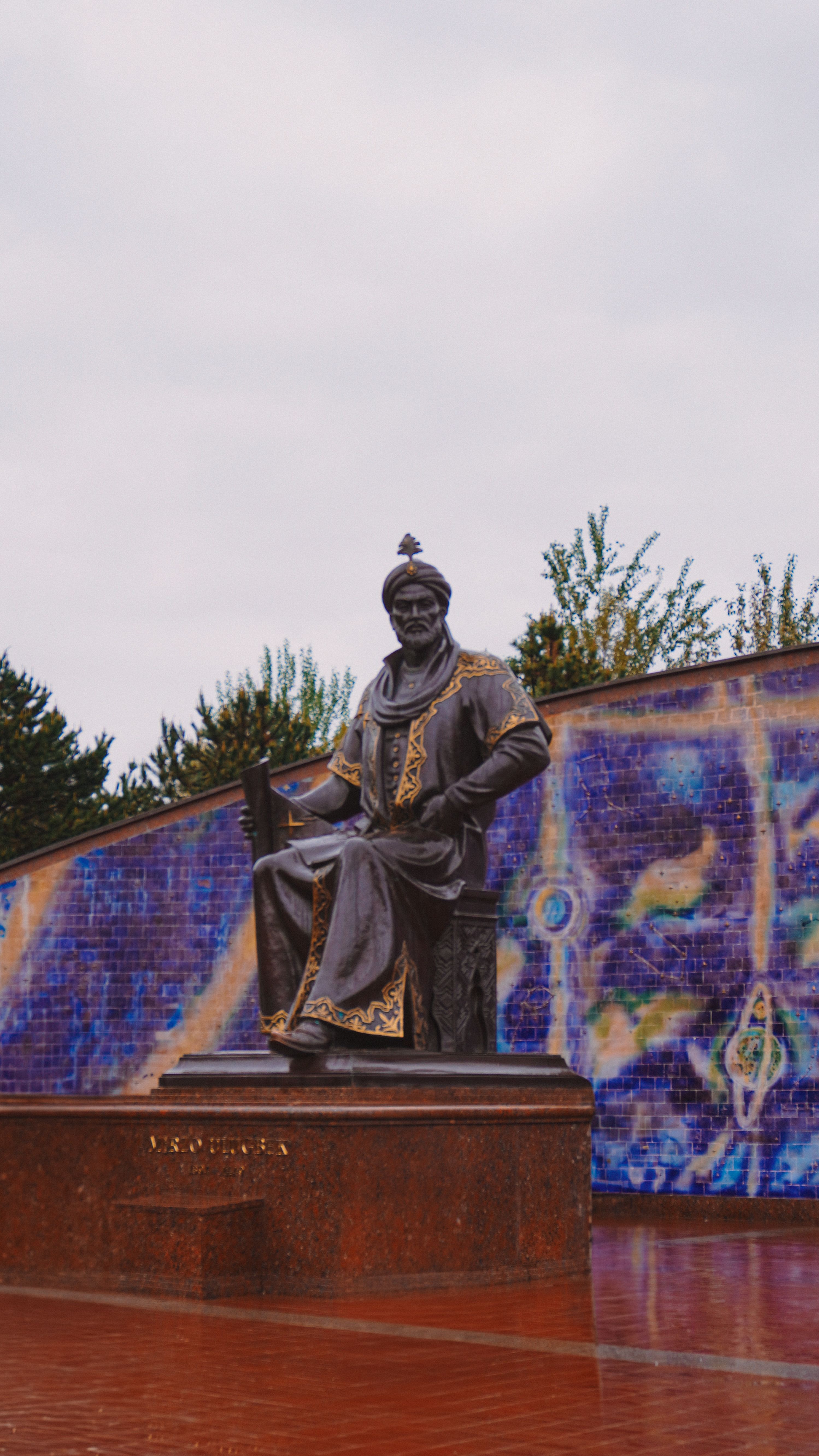 Bronze statue of Amir Timur in Samarkand, Uzbekistan with vibrant mosaic backdrop.