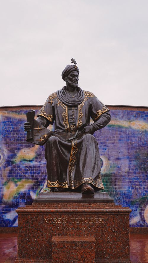 Free Elegant statue of Ulugh Beg in Samarkand, Uzbekistan, set against a vibrant mosaic backdrop. Stock Photo