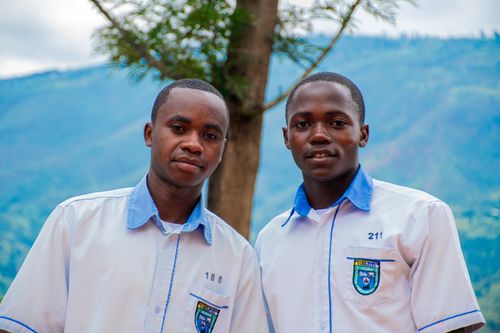 Free Portrait of two students in uniforms set against a scenic mountain backdrop. Stock Photo