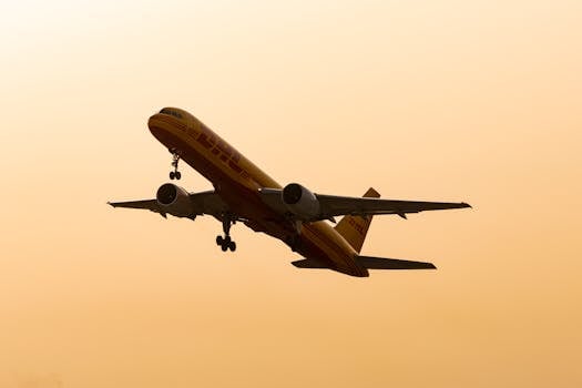 Cargo airplane flying in silhouette against a warm sunset sky.