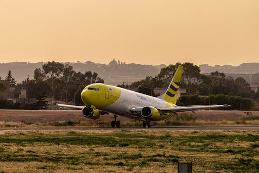 A yellow and white cargo plane is taxiing on the runway with a sunset backdrop, ready for takeoff.