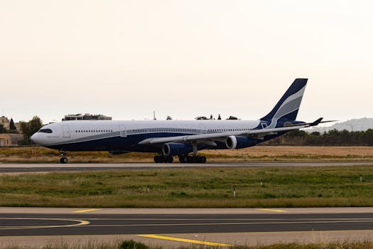 Photograph of a commercial airplane taxiing on an airport runway during sunset, with clear skies.