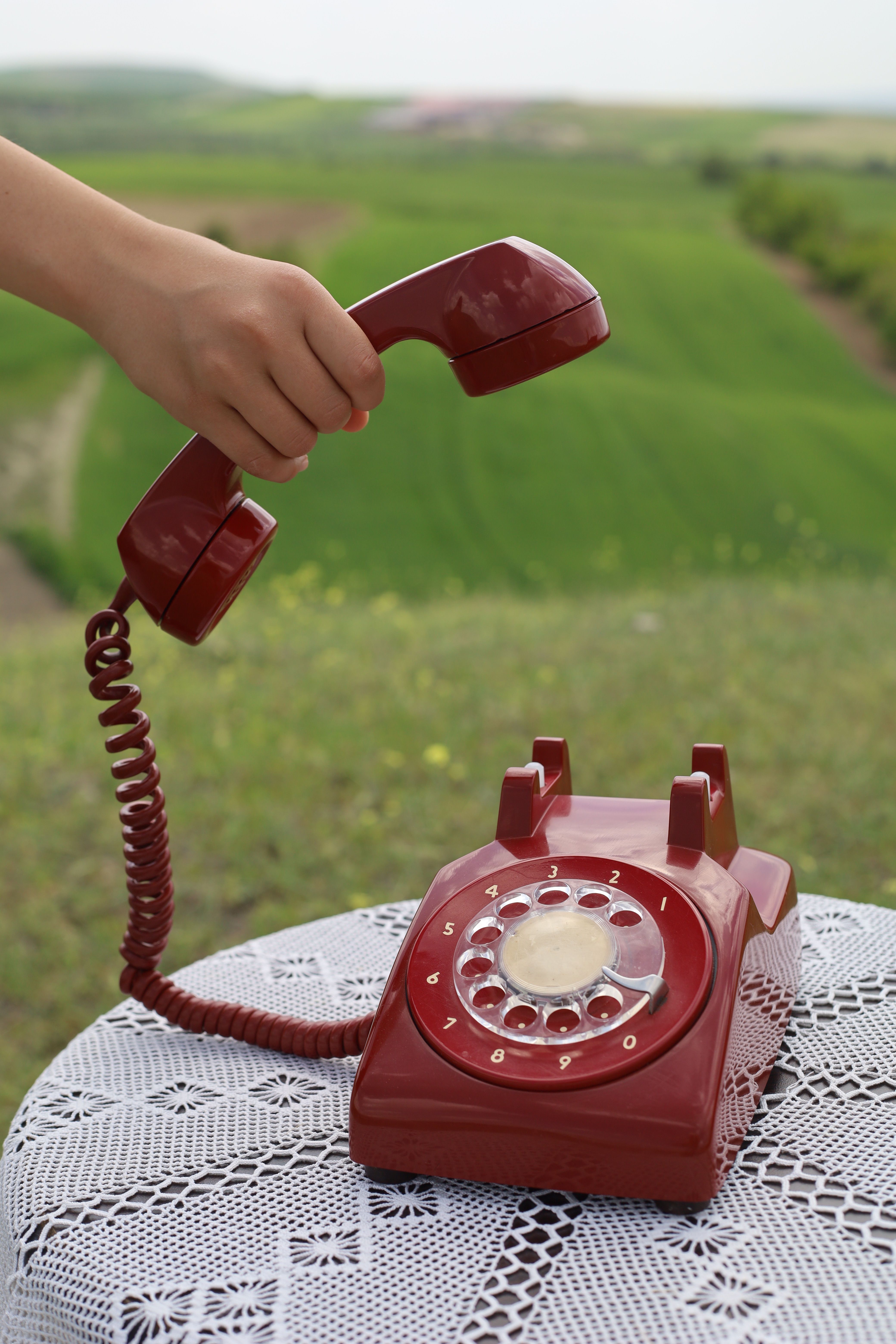 Hand Picking Up Vintage Red Rotary Phone Outdoors · Free Stock Photo