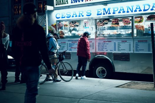 Vibrant urban scene of people enjoying a food truck at night in New York City.