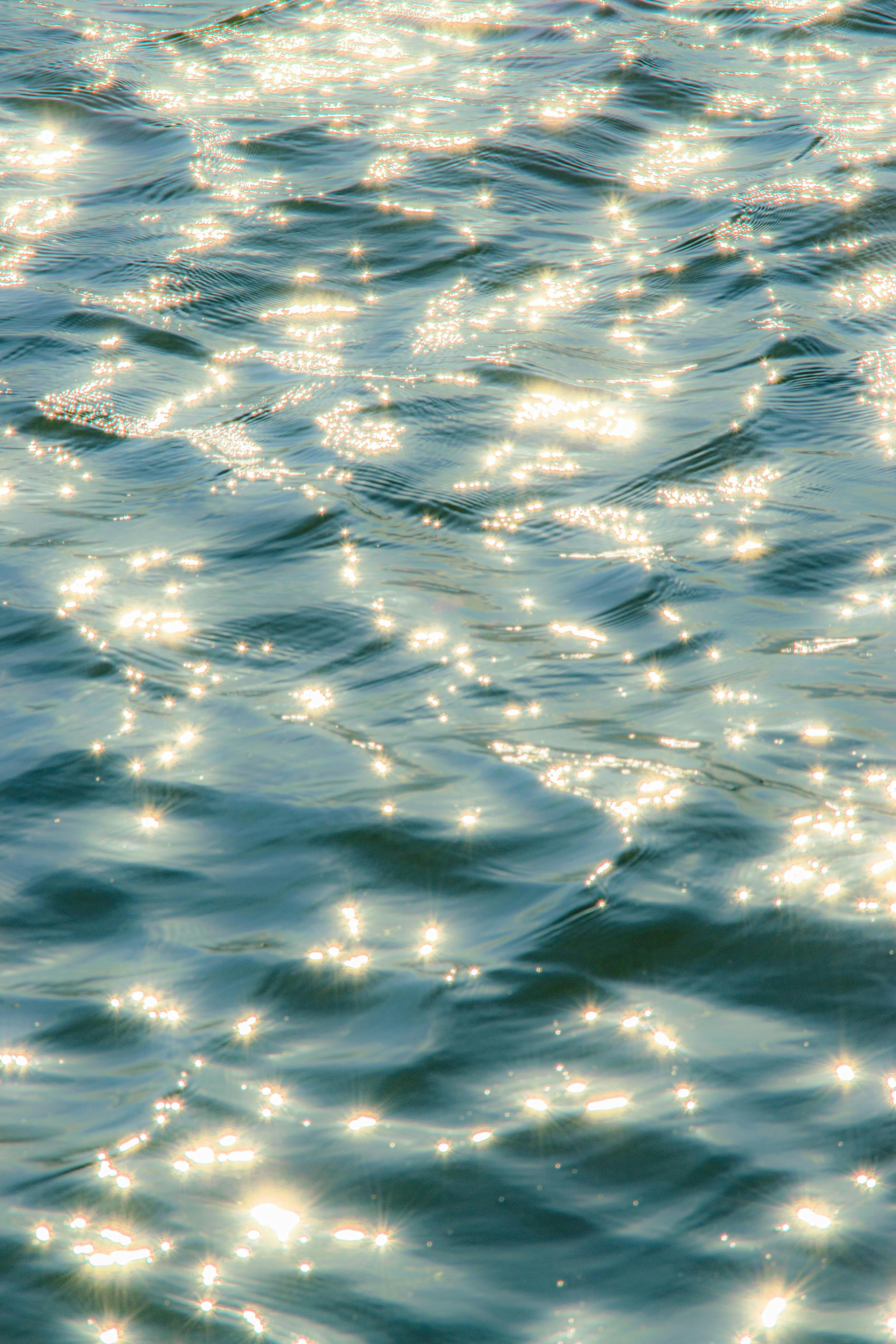 Bright and shimmering sunlight reflecting off gentle ocean waves, creating a serene and sparkling effect.