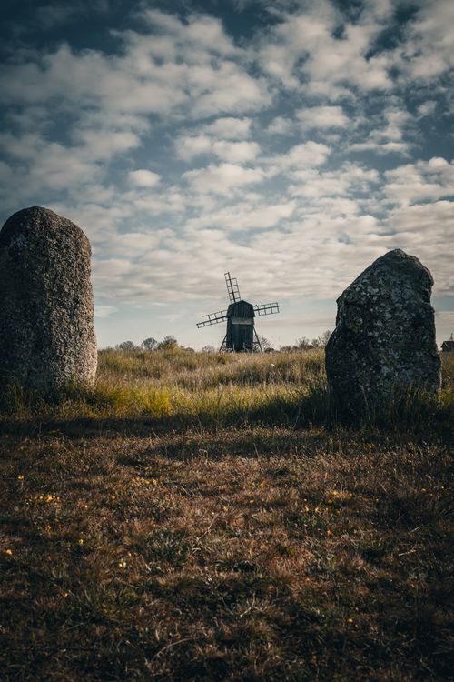 Free Scenic view of an old windmill surrounded by standing stones under a vibrant sky. Stock Photo