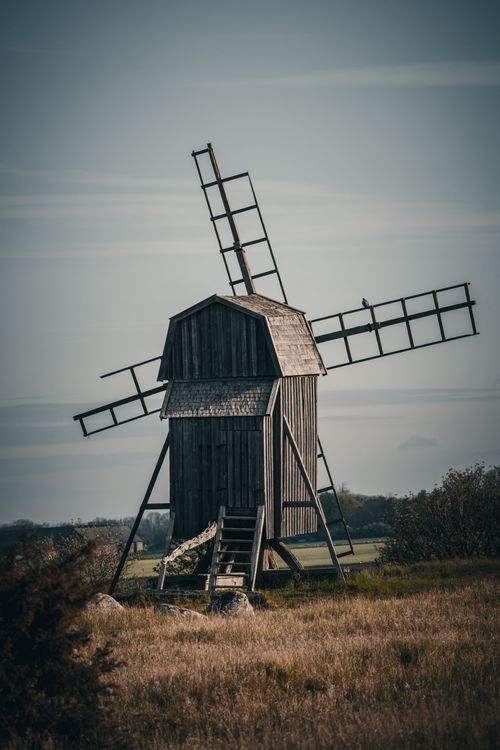 Free Vintage wooden windmill in a rural landscape, evoking a serene and historical atmosphere. Stock Photo