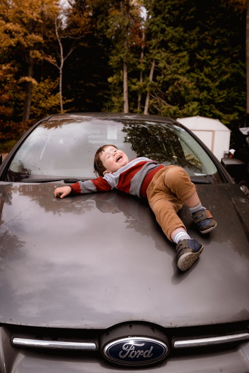 Free Photo of Boy Lying Down on Car Hood Stock Photo