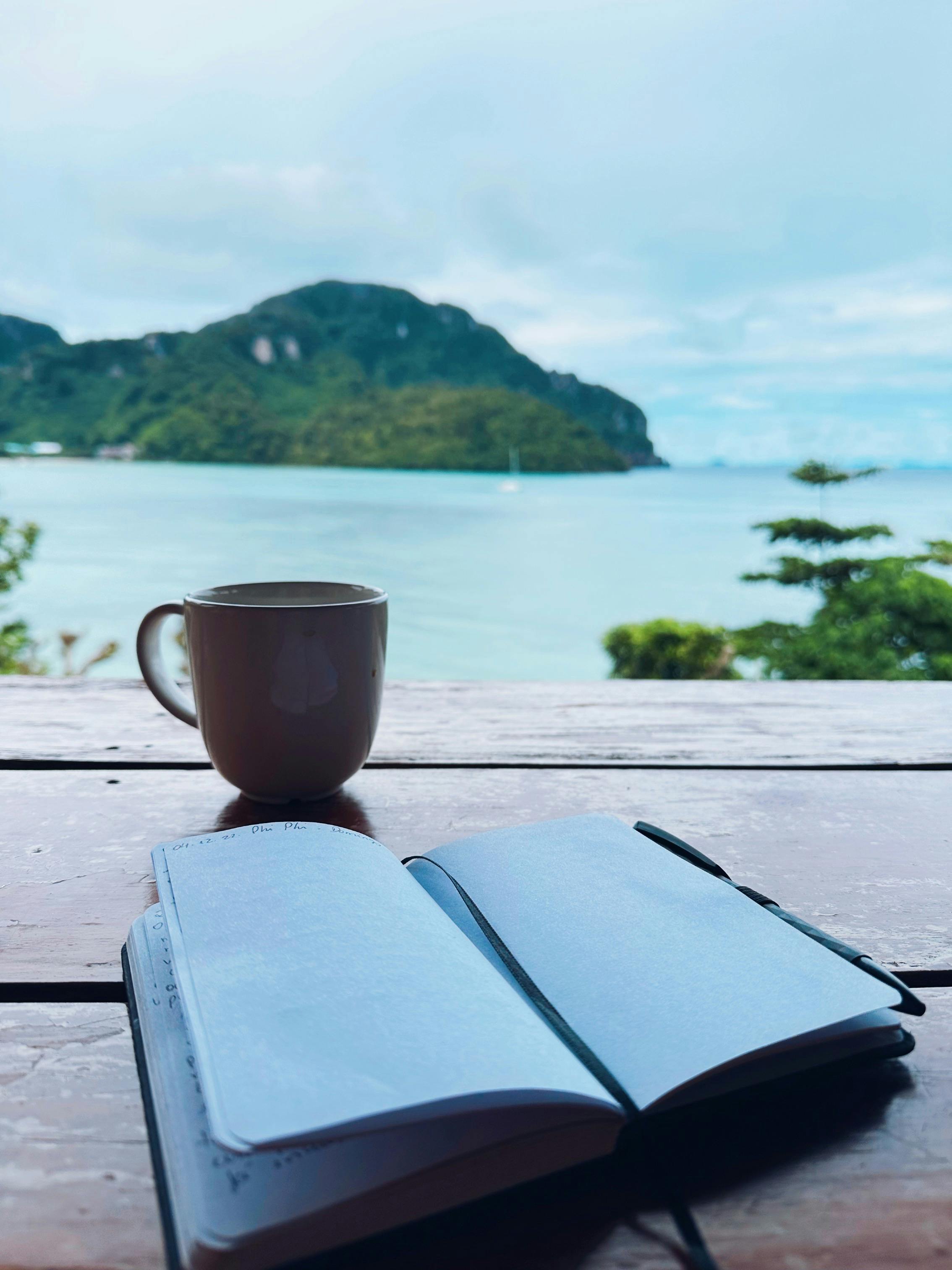 A journal and coffee beside the sea, the kind of quiet scene retreat brochures use to make grief look orderly.