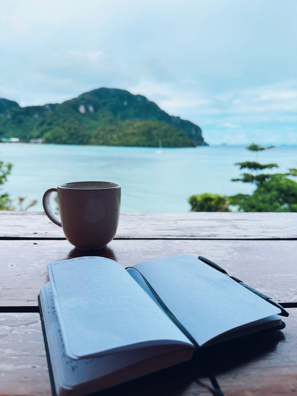 A journal and coffee beside the sea, the kind of quiet scene retreat brochures use to make grief look orderly.