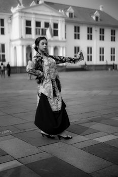 A woman in traditional attire performing dance outside a historic building.