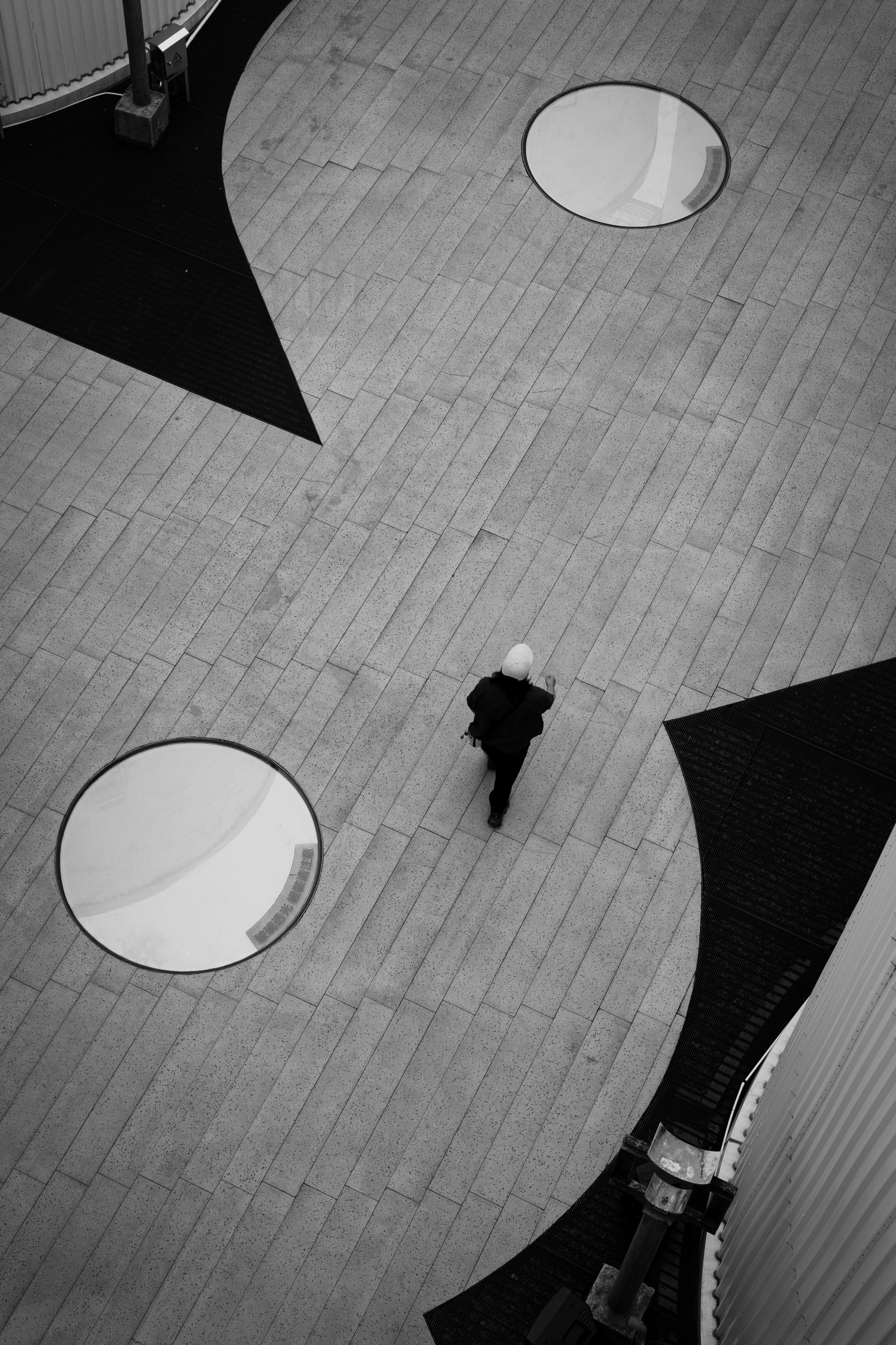 A striking aerial view of a solitary figure walking in a modern urban environment.