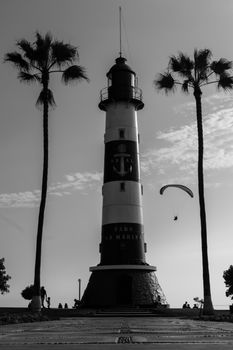 Monochrome image of the iconic Faro La Marina lighthouse in Miraflores, Lima with palm trees.