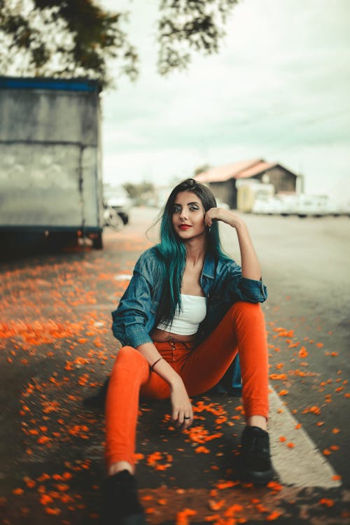 Free Photo of Woman in Blue Denim Jacket and Orange Pants Posing While Sitting on the Road Stock Photo