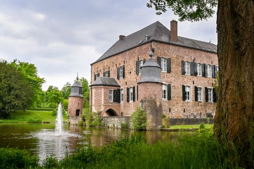 Free Charming medieval castle in Kerkrade, Limburg, reflecting in a pond with a fountain. Stock Photo
