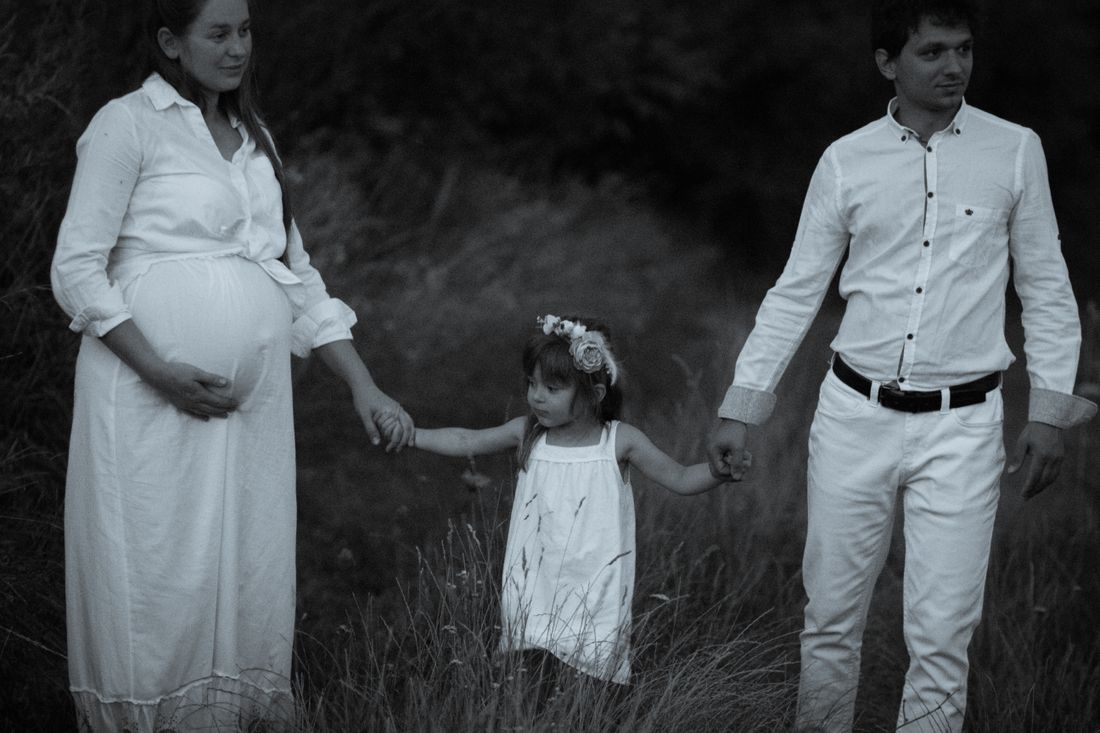 An expectant mother outdoors with her partner and older child