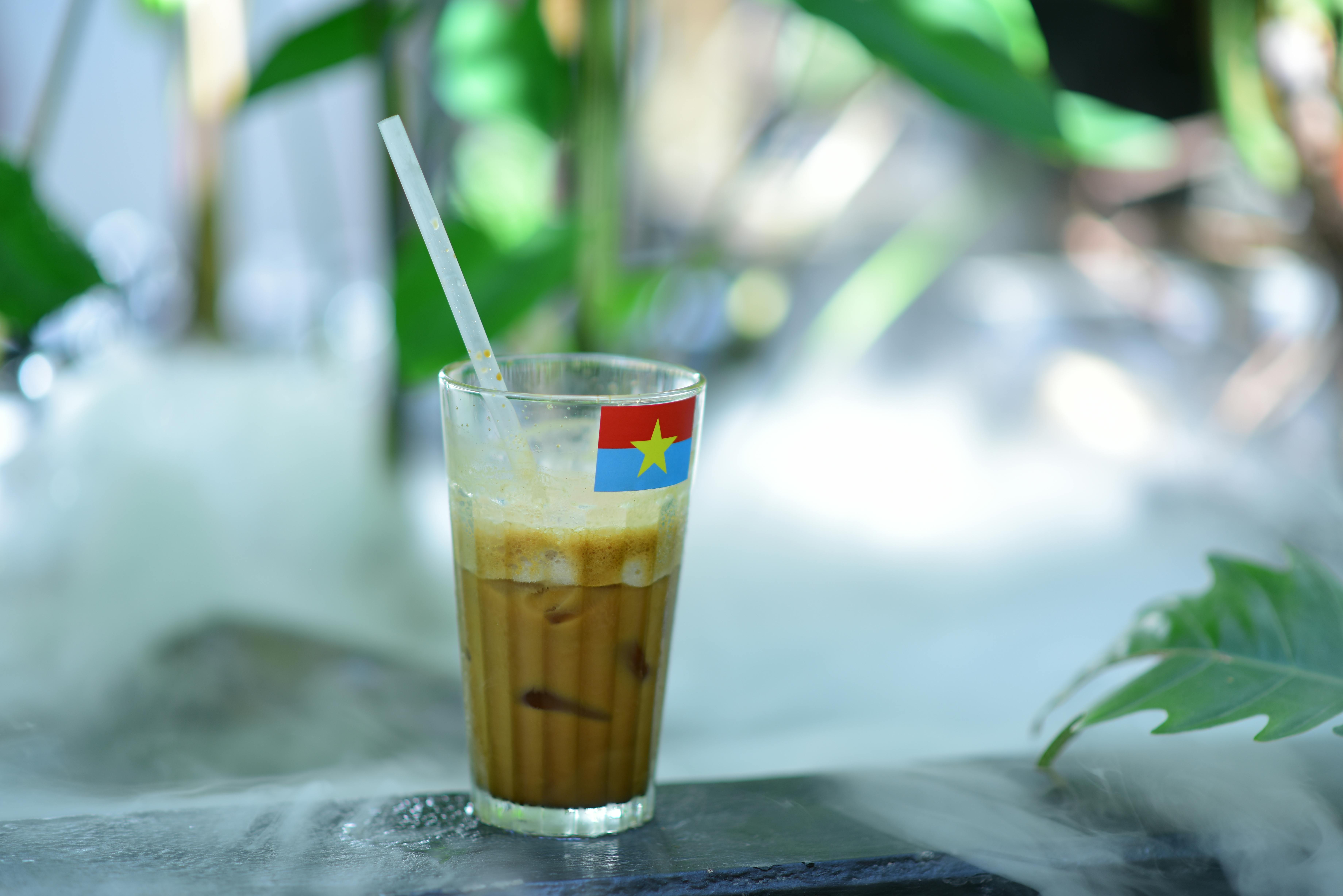 Iced coffee drink with a flag straw on a misty table, tropical vibe.