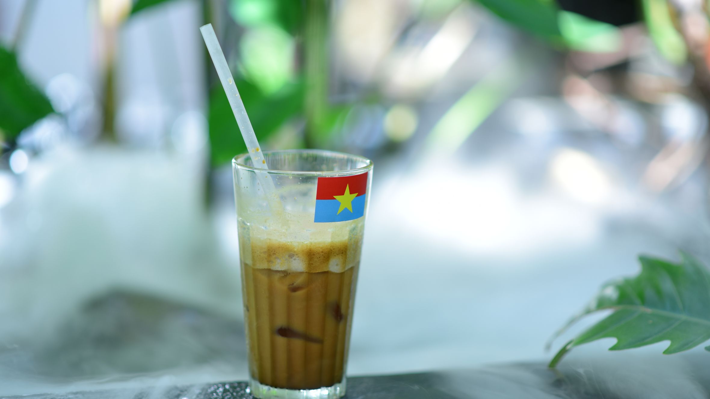 Iced coffee drink with a flag straw on a misty table, tropical vibe.